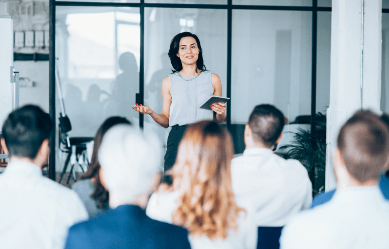 A spokesperson stands in front of an audience delivering a speech