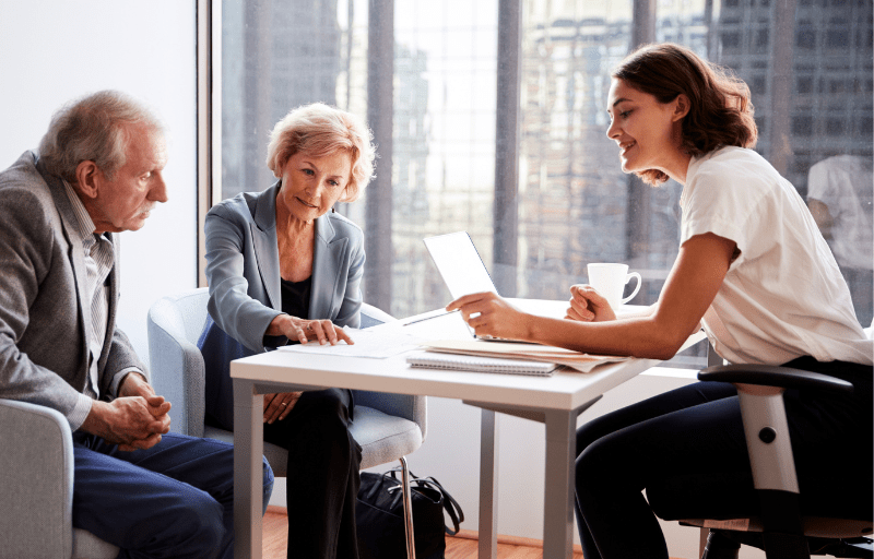 A solicitor sits with her elderly clients, advising them on a legal matter