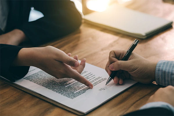 Close-up of person signing a contract with a solicitor