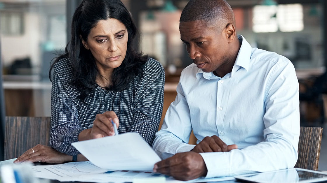 Two colleagues sat together discussing a document.