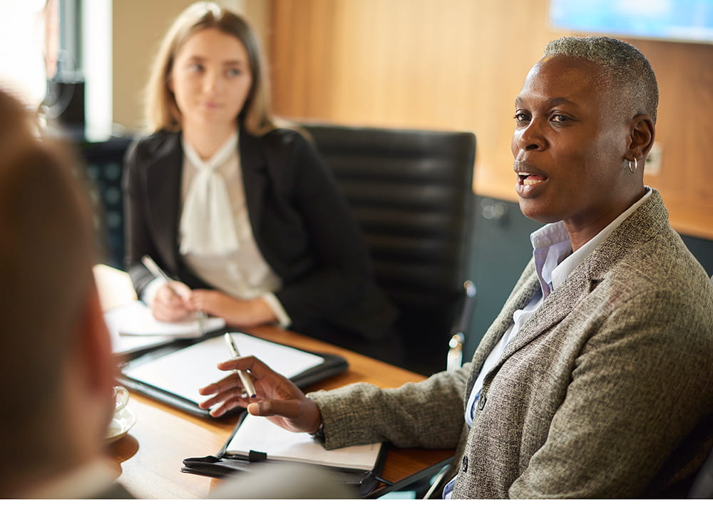 Black woman with short hair speaks to unseen listener in board room