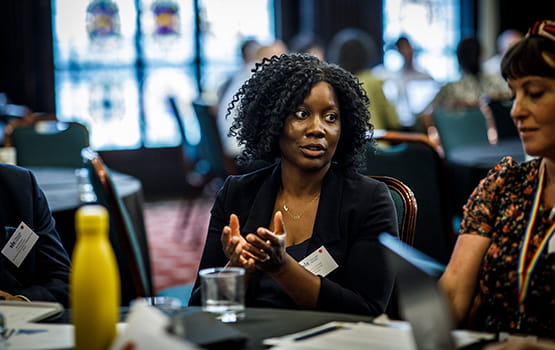 A woman sat at a table, engaging in a conversation, at the In-house Counsel Strategic Forum.