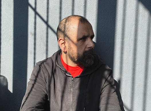 A man sits behind the shadows of bars.