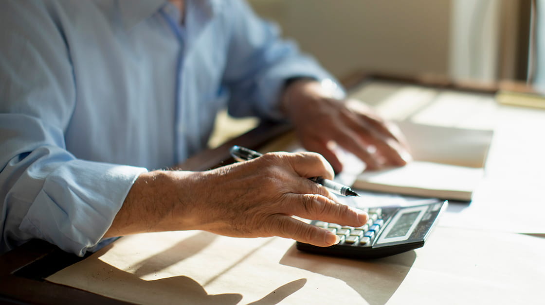 Close-up of older man using calculator