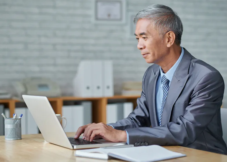 Older man in suit working on laptop